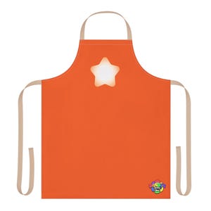 Puede incluir: Delantal naranja con un diseño de estrella blanca y correas beige. El delantal tiene un logotipo colorido en la esquina inferior derecha. Ideal para cocinar y hornear.