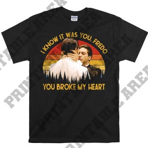May include: Black t-shirt with a vintage-style graphic of two men. The graphic features a sunset background with the text "I know it was you, Fredo. You broke my heart."