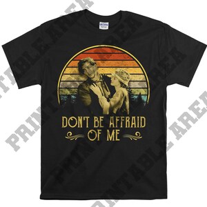 May include: Black t-shirt with a vintage-style image of a couple in front of a sunset. The text "Don't Be Afraid Of Me" is printed below the image.