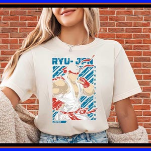Op de afbeelding: Een crèmekleurig T-shirt met korte mouwen en een grafische print van het personage Ryu uit Street Fighter. Het ontwerp bevat de tekst RYU-JPN en STREET FIGHTER in blauw en rood, met een gestileerde illustratie van het personage in een witte gi.