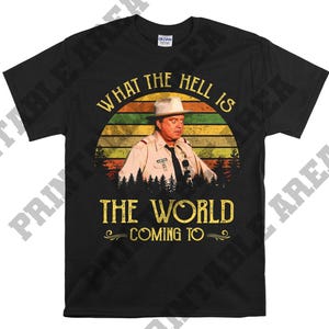 May include: Black t-shirt with a vintage-style graphic of a man in a ranger uniform. The graphic says "What the hell is the world coming to?"