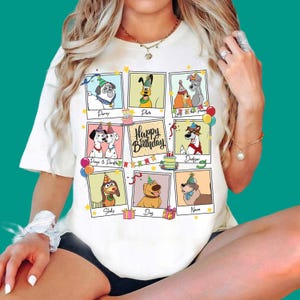 Może przedstawiać: Biały t-shirt z nadrukiem graficznym przedstawiającym różne psy z bajek w czapkach urodzinowych w ramkach typu polaroid. Środkowa ramka zawiera napis Happy Birthday, otoczony ilustracjami tortów urodzinowych, balonów i prezentów.