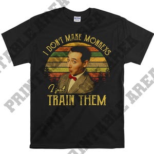 以下が含まれることがあります： 赤い蝶ネクタイをした男性のヴィンテージスタイルのグラフィックがプリントされた黒いTシャツ。グラフィックには「サルは作らない、ただ訓練するだけ」と書かれている。