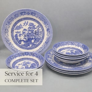 May include: A complete blue and white Willow pattern dinnerware set for four. The set includes dinner plates and bowls. The plates and bowls have a detailed landscape design with a blue and white color scheme.