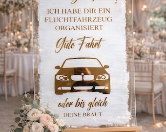 Puede incluir: Un letrero de boda de acrílico transparente sobre un caballete de madera con pinceladas blancas y texto dorado que dice: Letzte Chance zur Flucht! ICH HABE DIR EIN FLUCHTFAHRZEUG ORGANISIERT Gute Fahrt oder bis gleich DEINE BRAUT. Incluye un gráfico de coche.