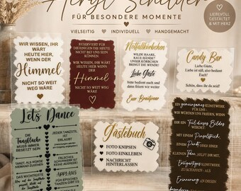 Puede incluir: Una colección de letreros rectangulares de acrílico con varios diseños de texto en alemán en dorado, negro y blanco. Los letreros tienen bordes pintados decorativos e incluyen frases como 'Lets Dance', 'Gästebuch' y 'Candy Bar' para decoración.