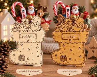 Puede incluir: Dos adornos navideños de madera en forma de calcetín, uno claro y otro teñido, con los nombres Alessia y Lukas grabados. Cada calcetín está relleno de bastones de caramelo en miniatura, figuras de Papá Noel de chocolate y galletas.