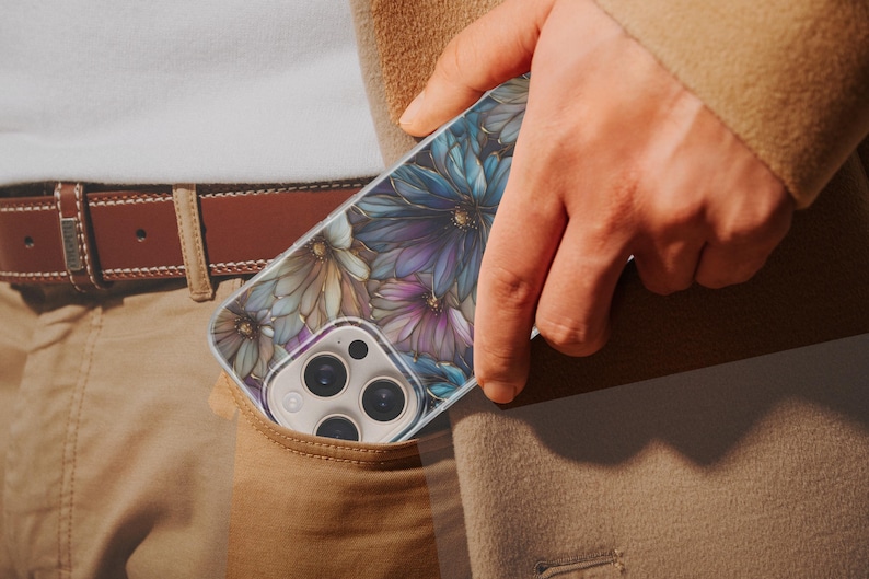 Puede incluir: Un tel&eacute;fono inteligente en una funda con estampado floral es parcialmente visible en un bolsillo. La funda presenta dise&ntilde;os de flores azules, moradas y doradas. La persona lleva un cintur&oacute;n marr&oacute;n y pantalones color caqui.