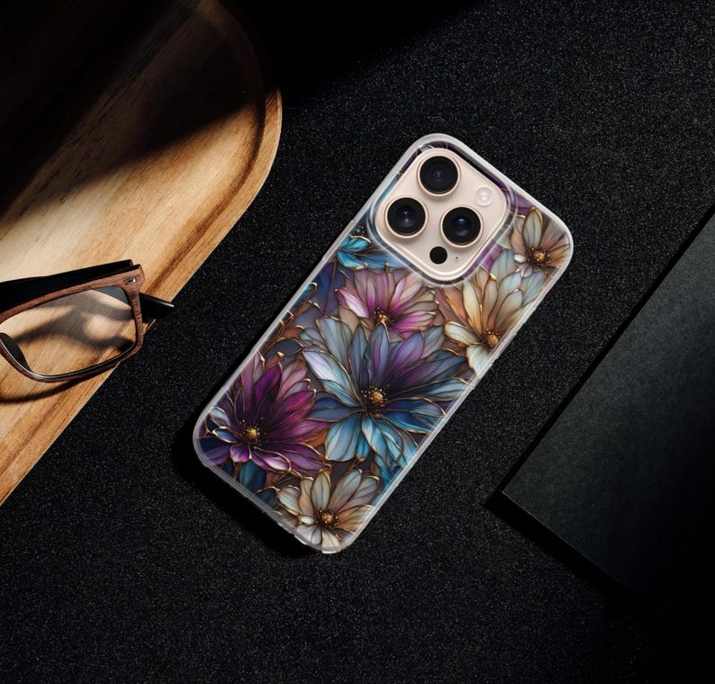 Puede incluir: Una funda transparente para tel&eacute;fono con un dise&ntilde;o floral en tonos morados, azules y dorados. La funda tiene un acabado brillante y est&aacute; dise&ntilde;ada para un smartphone. Las flores son detalladas y est&aacute;n dispuestas en un patr&oacute;n repetitivo.