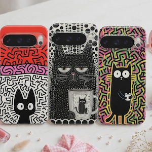 May include: Three smartphone cases featuring cat illustrations. The left case has a red and white maze pattern with a black cat. The center case is black with white dots and a cat holding a mug. The right case has a colorful maze background with a black cat.