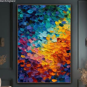 Könnte beinhalten: Großes abstraktes Gemälde im strukturierten Impasto-Stil. Das Kunstwerk zeigt eine lebendige Palette aus Blau-, Gelb-, Orange- und Lilatönen, die eine dynamische und farbenfrohe Komposition erzeugt. Das Gemälde ist gerahmt und an einer dunkelgrauen Wand ausgestellt.