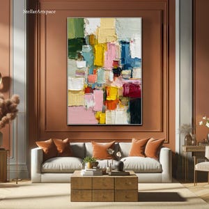 May include: Abstract oil painting with a textured surface, featuring a vibrant mix of colors including pink, yellow, green, and blue. The artwork is framed and hangs above a sofa in a living room setting. The text "StellarArtspace" is in the upper left corner.