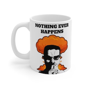 May include: White ceramic mug with the phrase "NOTHING EVER HAPPENS" in black block letters. The mug features a graphic of a man with a finger to his lips, with an orange explosion behind him.