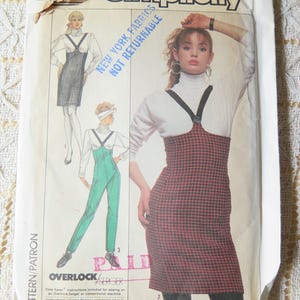 Può includere: Un modello di cucito Simplicity vintage, taglia N (10+12+14), con illustrazioni di una donna con un abito con bretelle e una tuta. Il modello include istruzioni per cucire con una macchina overlock/serger. I colori principali sono bianco, nero e rosso.
