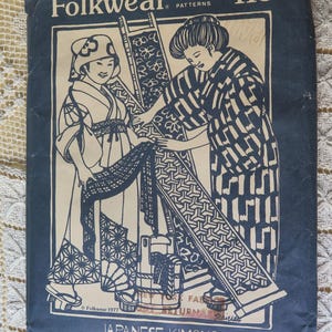 May include: A vintage Folkwear pattern envelope, featuring a blue and white illustration of two women in Japanese kimono. The text reads "Japanese Kimono" and includes details about sewing instructions and embroidery techniques.