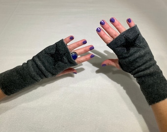 May include: A pair of gray fingerless gloves with black star embroidery. The gloves are made of a soft, fuzzy material.