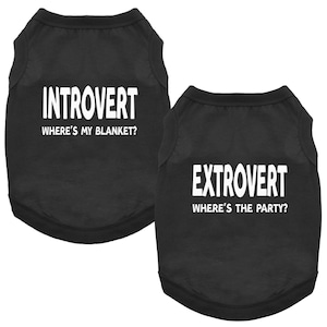 Może przedstawiać: Dwie czarne koszulki dla psów z białym tekstem. Jedna koszulka mówi "Introwertyk, Gdzie jest mój koc?" Druga mówi "Ekstrawertyk, Gdzie jest impreza?" Koszulki są bez rękawów i wykonane z miękkiego materiału.