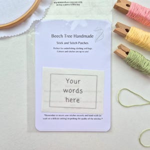 May include: A clear plastic packet featuring a white patch with the text "Your words here" within a frame. The packet also displays "Beech Tree Handmade" and "Stick and Stitch Patches". Embroidery thread spools in pink, yellow, and green are visible.
