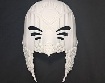 May include: White plastic mask with intricate details and a geometric design. The mask has eye holes and a pointed chin.