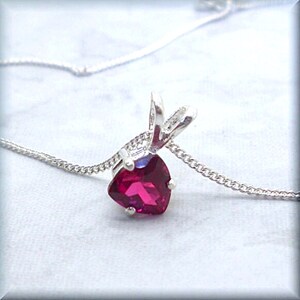 May include: A silver pendant necklace with a heart-shaped ruby gemstone.