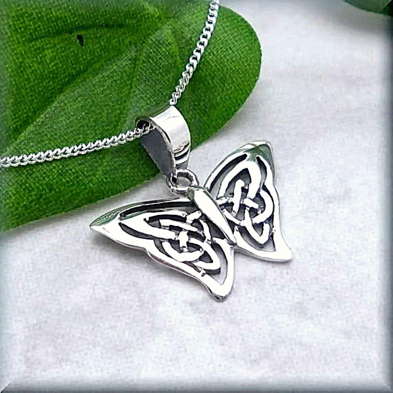 May include: A silver butterfly pendant necklace featuring a Celtic knot design. The pendant is detailed and intricate, with a delicate chain.
