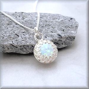 May include: A silver necklace with a white opal pendant set in a delicate filigree design.