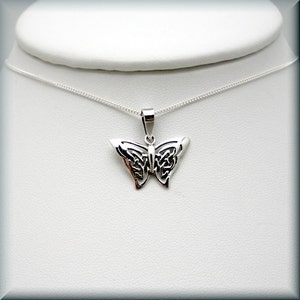 May include: A silver butterfly pendant necklace with a Celtic knot design. The pendant is on a silver chain.