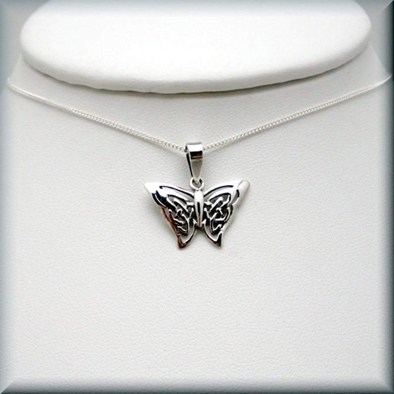 May include: A silver butterfly pendant necklace with a Celtic knot design. The pendant is on a silver chain.