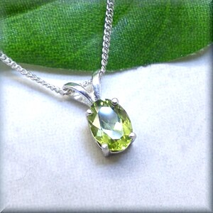 May include: A silver chain necklace with a green oval peridot pendant.