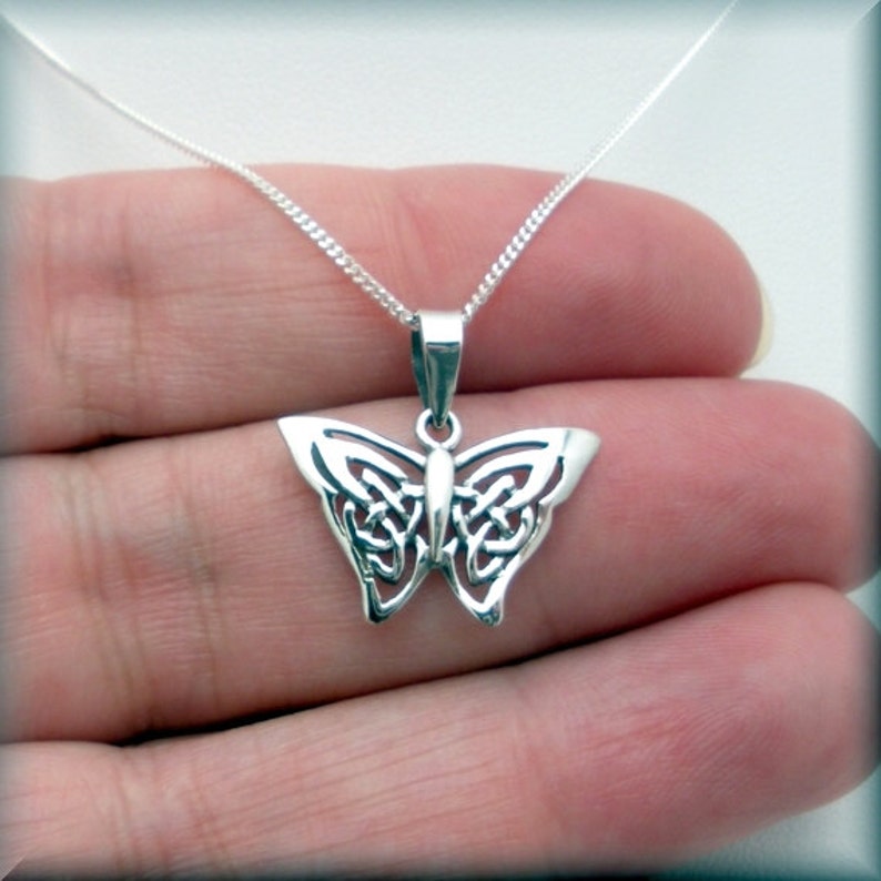May include: A silver Celtic knot butterfly pendant necklace. The pendant is detailed and intricate, with a delicate chain.
