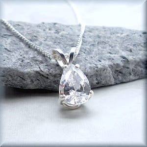 May include: A silver necklace with a pear-shaped clear crystal pendant.