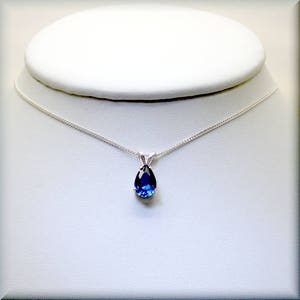 Pode incluir: Um colar de corrente de prata com um pingente de pedra preciosa azul em forma de l&aacute;grima.