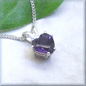 May include: A silver heart-shaped pendant necklace with a purple gemstone.