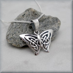 May include: A silver Celtic knot butterfly pendant necklace. The pendant is detailed and intricate, with a delicate chain.