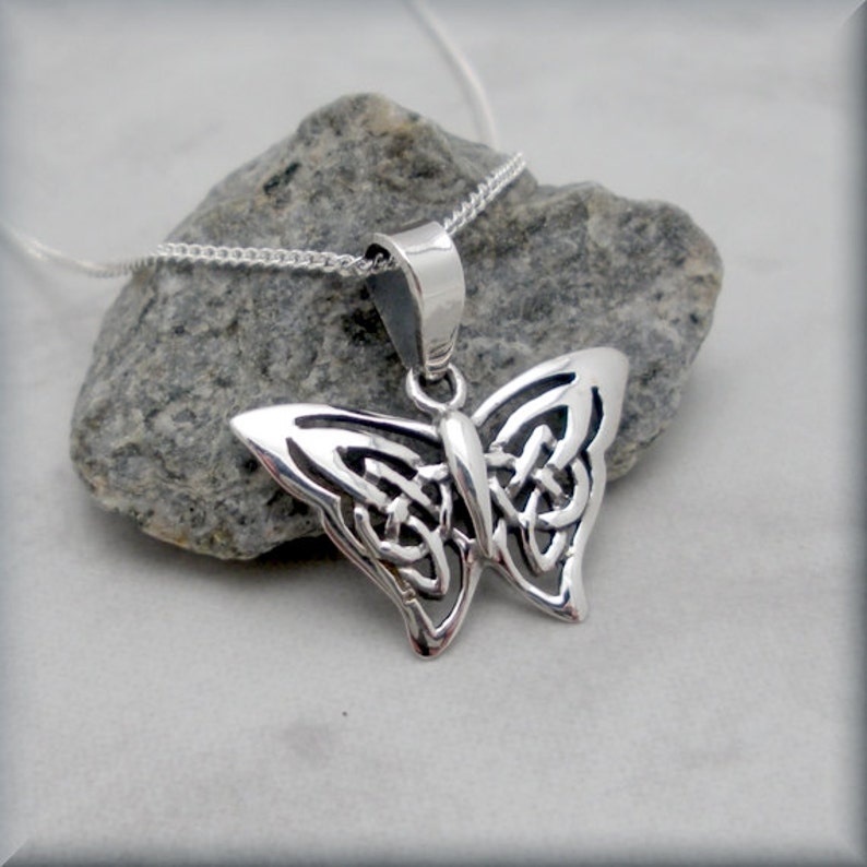 May include: A silver Celtic knot butterfly pendant necklace. The pendant is detailed and intricate, with a delicate chain.