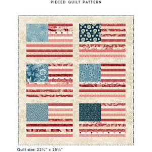 May include: A pieced quilt pattern titled Laundry Basket Quilts Made in USA - Mini. The design features six flag-inspired blocks with red, white, and blue floral and patterned fabrics. The finished quilt size is listed as 22.25 inches by 26.5 inches.