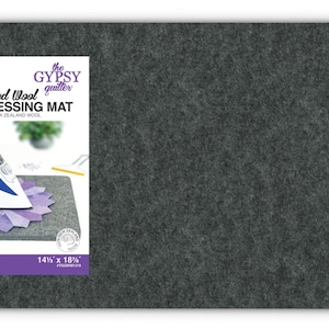 May include: A dark grey felted wool pressing mat from "the Gypsy Quilter." The mat is rectangular with rounded corners and features the text "Felted Wool PRESSING MAT" and "100% New Zealand Wool." It measures approximately 37 x 46 cm.