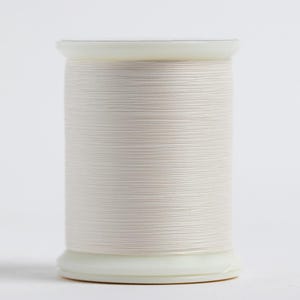 May include: A spool of off-white thread, tightly wound and ready for sewing. The thread is a light, neutral color, and the spool has a white plastic base and top. The thread is neatly wrapped around the spool, creating a clean, organized appearance.