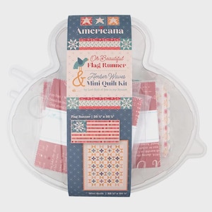 May include: A mini quilt kit in a clear plastic container. The kit includes fabric pieces and a printed label with the text "Americana," "Oh Beautiful Flag Runner & Amber Waves Mini Quilt Kit." The flag runner measures 26.5 x 66 inches.