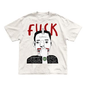 May include: A white short-sleeve t-shirt featuring a black and white line drawing of a person with a red mouth, giving the middle finger. The word FUCK is printed in red above the head. The shirt includes text about government and corruption.