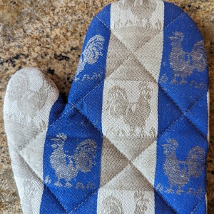 Puede incluir: Manopla de horno acolchada azul y blanca con un dise&ntilde;o de gallo. La manopla est&aacute; hecha de una tela suave y texturizada.