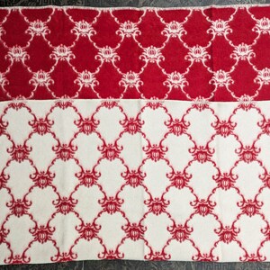 May include: Two blankets with a red and white floral pattern. The top blanket is red with white flowers and the bottom blanket is white with red flowers.