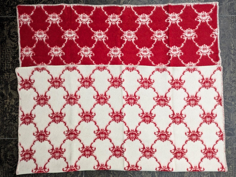 May include: Two blankets with a red and white floral pattern. The top blanket is red with white flowers and the bottom blanket is white with red flowers.