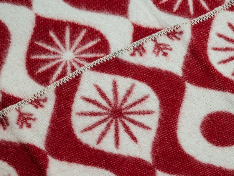 Puede incluir: Primer plano de un textil estampado en rojo y blanco. El dise&ntilde;o presenta un patr&oacute;n repetitivo de explosiones de estrellas estilizadas y formas curvas. Los bordes est&aacute;n acabados con una puntada en zigzag blanca.