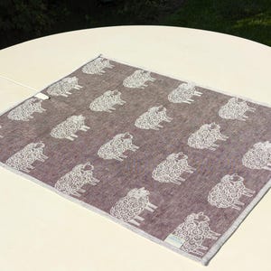 May include: A brown throw blanket with a white sheep pattern. The blanket is made of a soft, textured fabric.