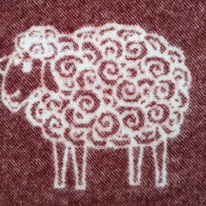 May include: A white sheep with a swirling pattern on a maroon background.