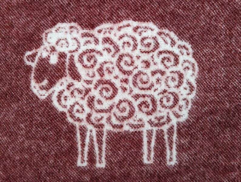 May include: A white sheep with a swirling pattern on a maroon background.