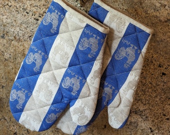 Puede incluir: Un par de guantes de horno a rayas azules y blancas con un diseño acolchado y un patrón de gallo.