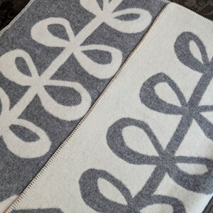 May include: A gray and white throw blanket with a repeating pattern of stylized leaves. The leaves are outlined in white on a gray background and gray on a white background.