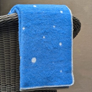 May include: A blue throw blanket with a white polka dot pattern, draped over a wicker chair.
